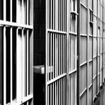 jail cell block corridor with metal bars and empty detention cells